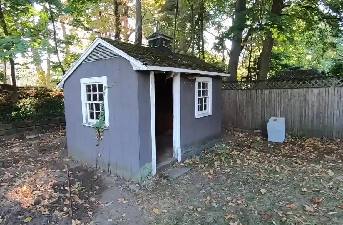 A Grey coloured Shed with background greenery ,before picture